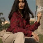 A serious brunette woman poses outdoors in Patna, India, showcasing a stylish look.